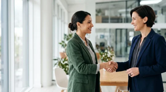 Deux professionnels se serrant la main dans un bureau lumineux, symbolisant la signature réussie d'un devis convertissant un prospect en client